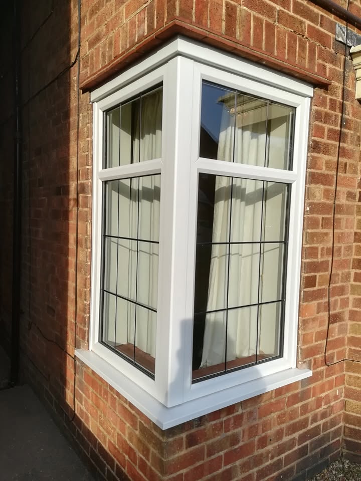 White uPVC fixed corner bay window on a brick property