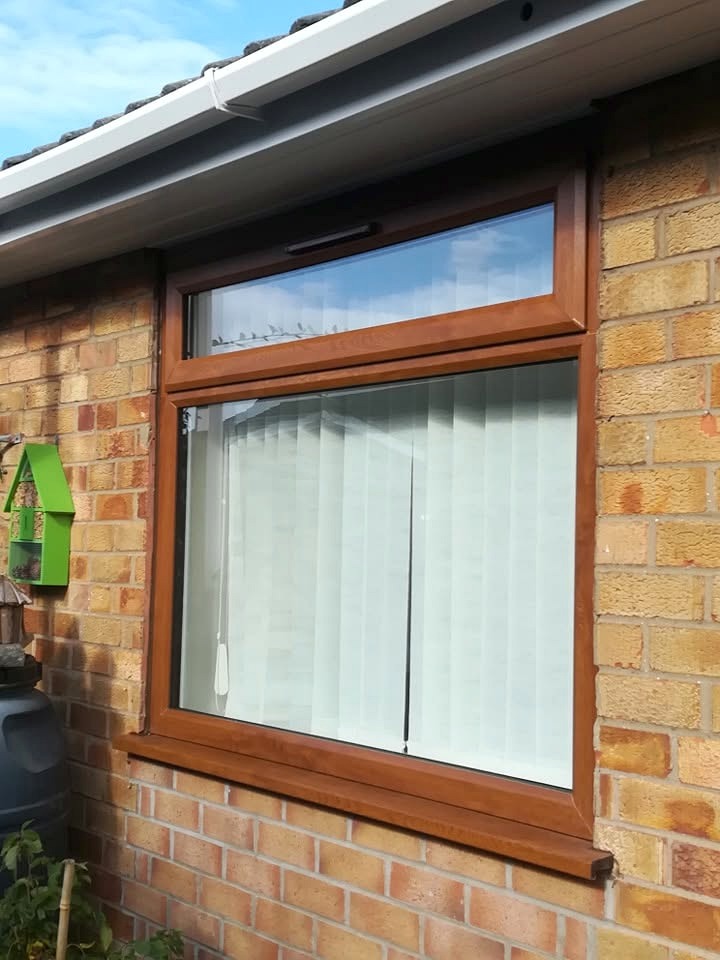 Woodgrain uPVC casement window on a brick property